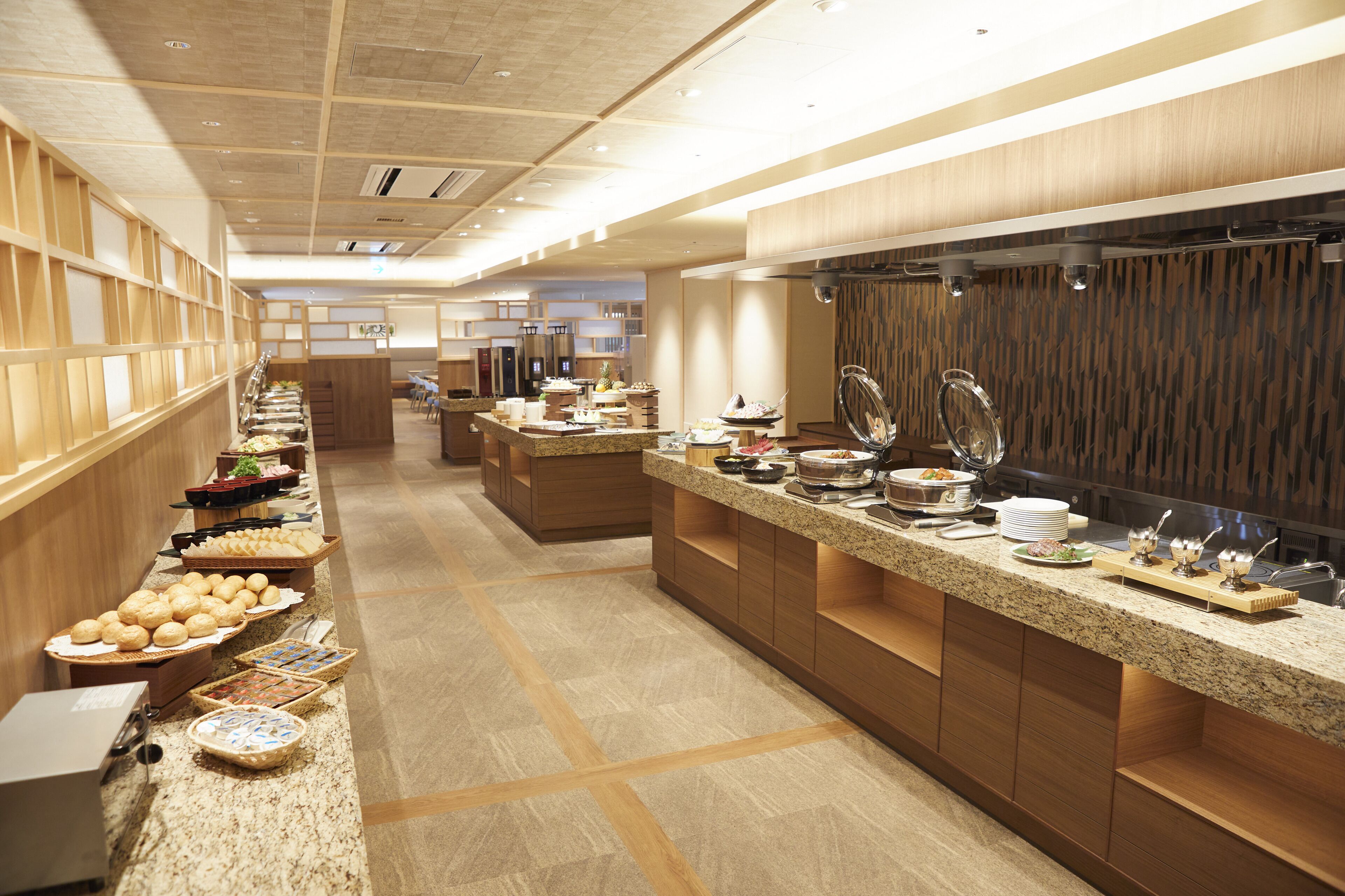 Una cocina moderna de hotel con mesas de buffet, paneles de madera y una larga barra con diferentes alimentos.