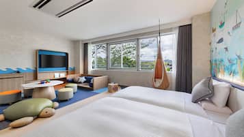A modern hotel room with a large bed, a flat-screen TV, a children's play area, and a view of the outdoors.