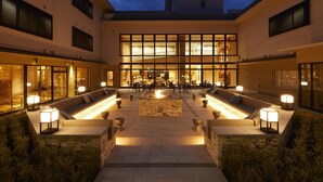 Un amplio espacio al aire libre con asientos y mesas, una chimenea central y ventanas grandes que permiten la entrada de luz natural.