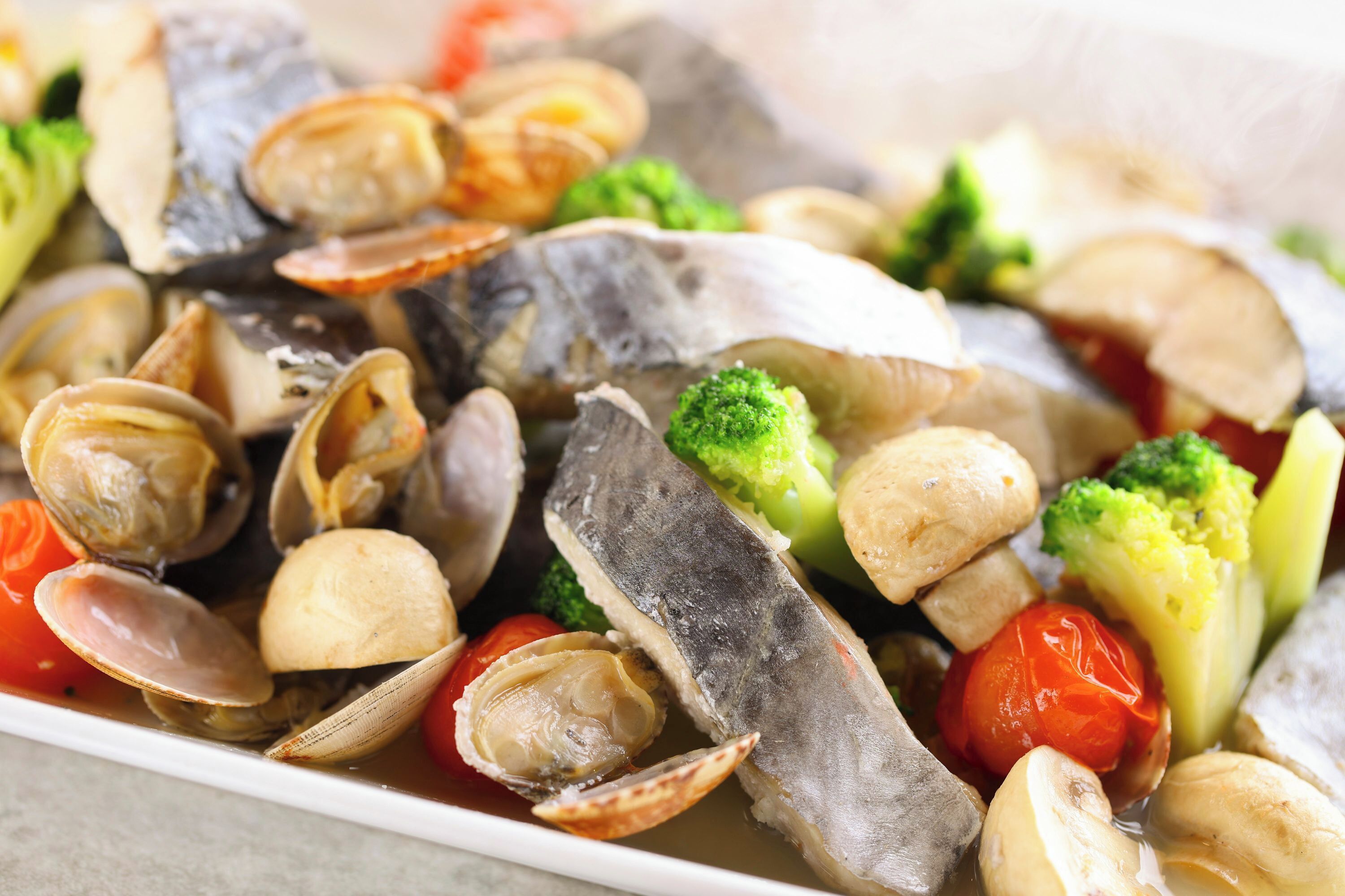 Prato com amêijoas, peixe, brócolis e tomates cereja.