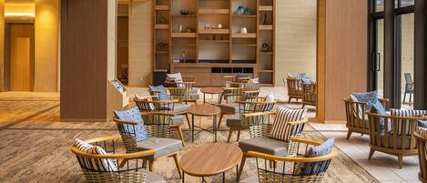 Un vestíbulo con muebles de mimbre, una mesa de centro y un estante grande con objetos decorativos.