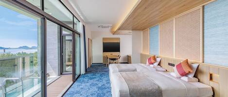 A modern hotel room with a balcony, a large bed, a desk, and a view of the outdoors.
