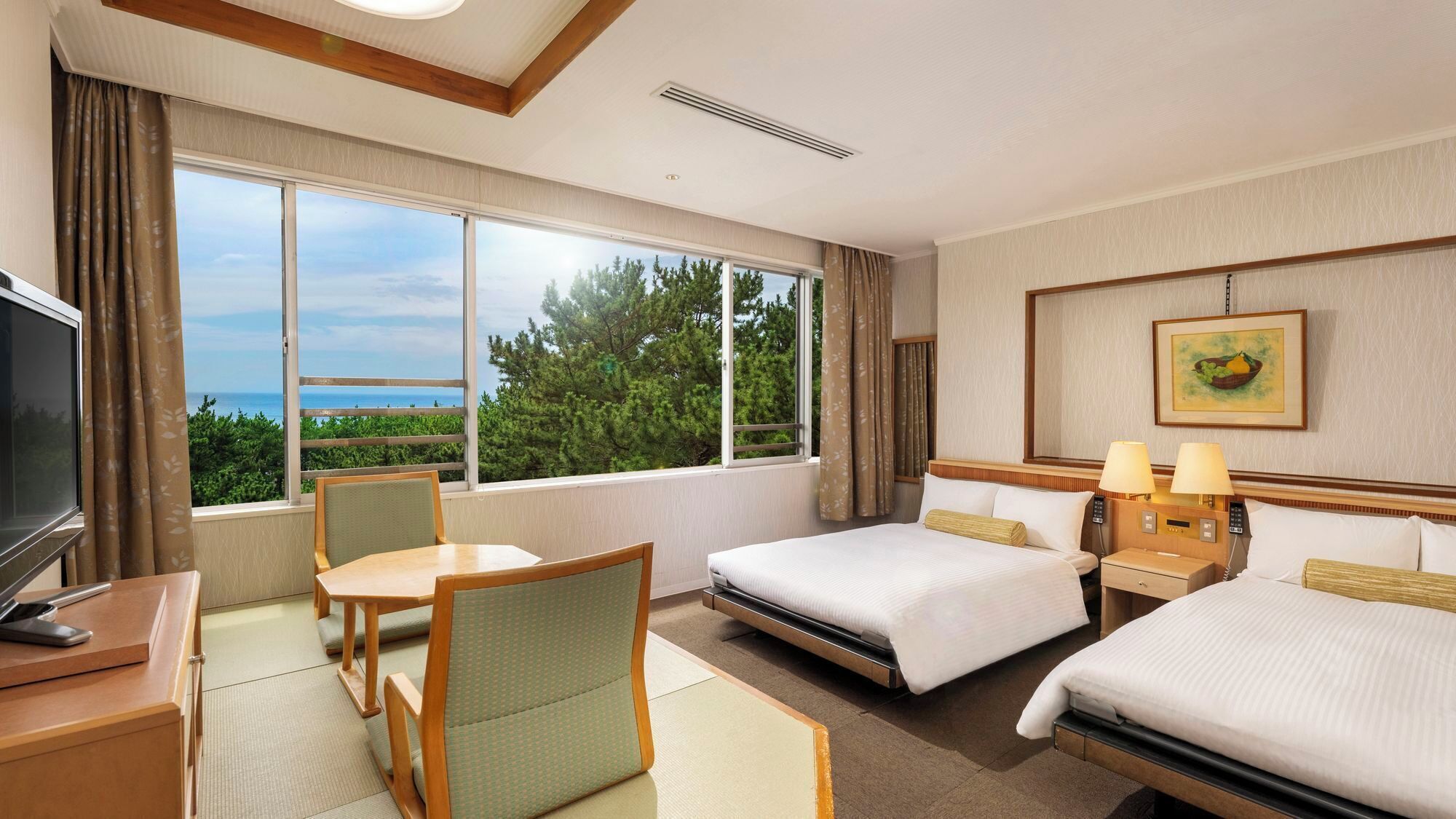 A hotel room with two beds, a desk, a chair, a TV, and a large window with a view.