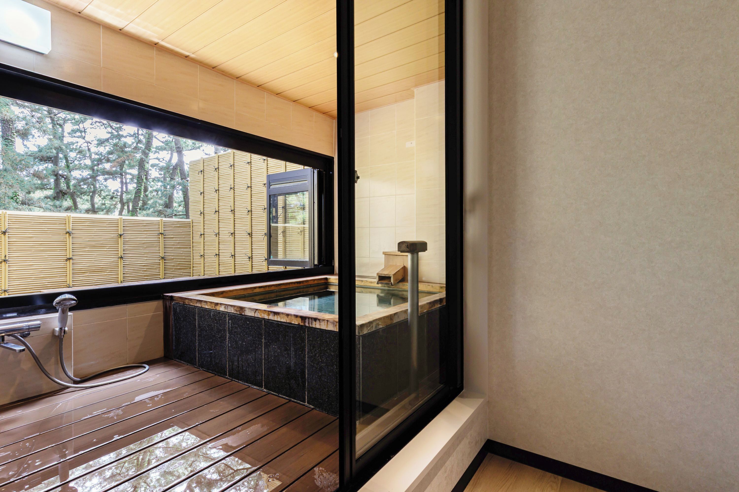 A modern bathroom with a wooden floor, a glass-enclosed hot tub, and a view of the outdoors.