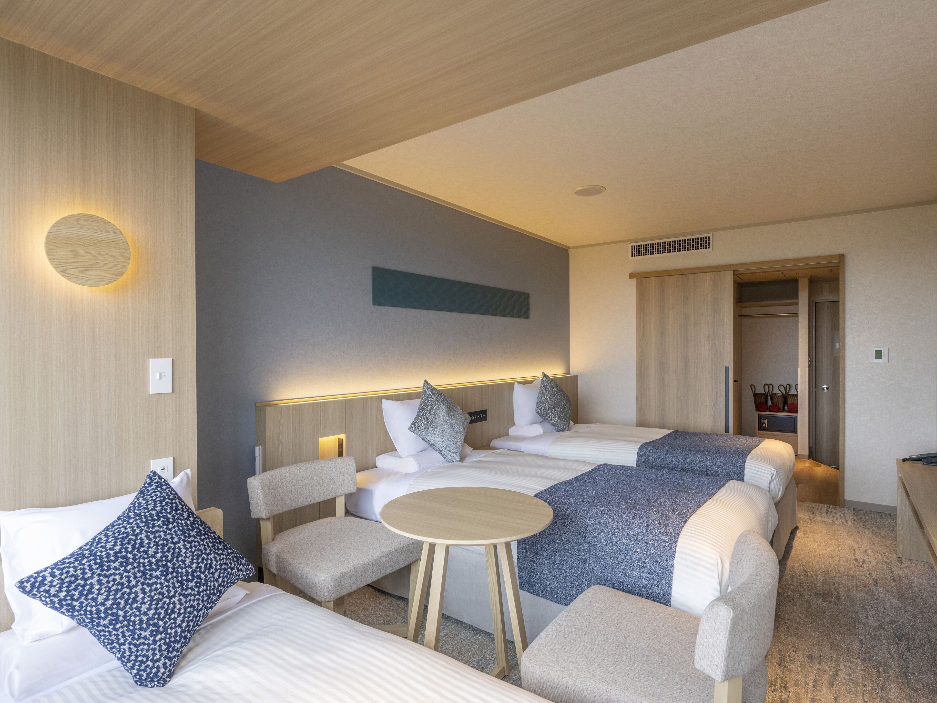 A hotel room with two beds, a small round table, and a wardrobe.