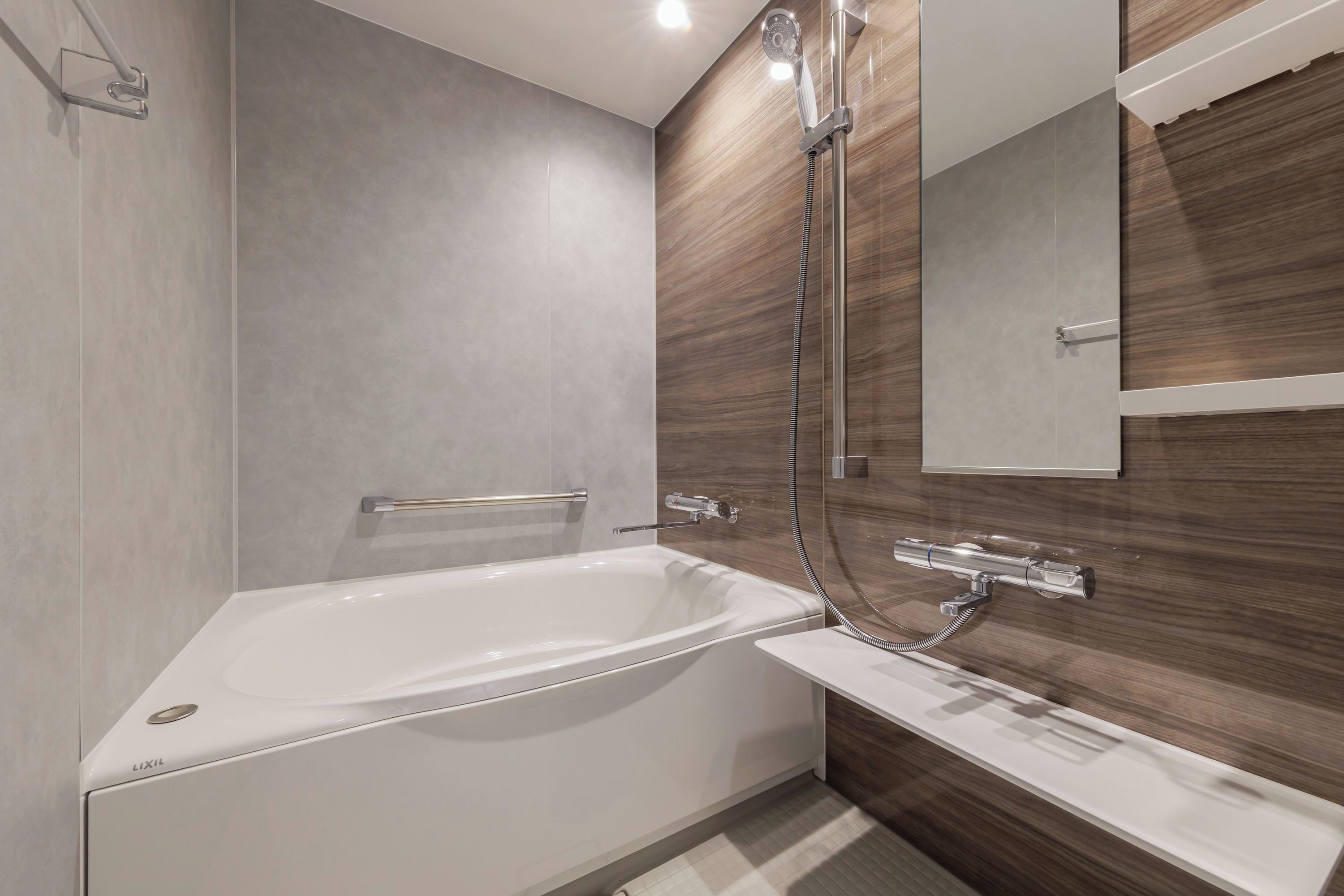 A modern bathroom with a white bathtub, a shower with a handheld hose, and a wooden vanity.