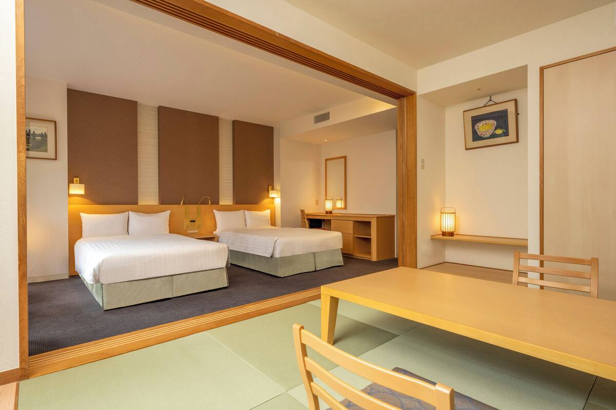 Una habitación de hotel con dos camas, un escritorio y una mesa de comedor.