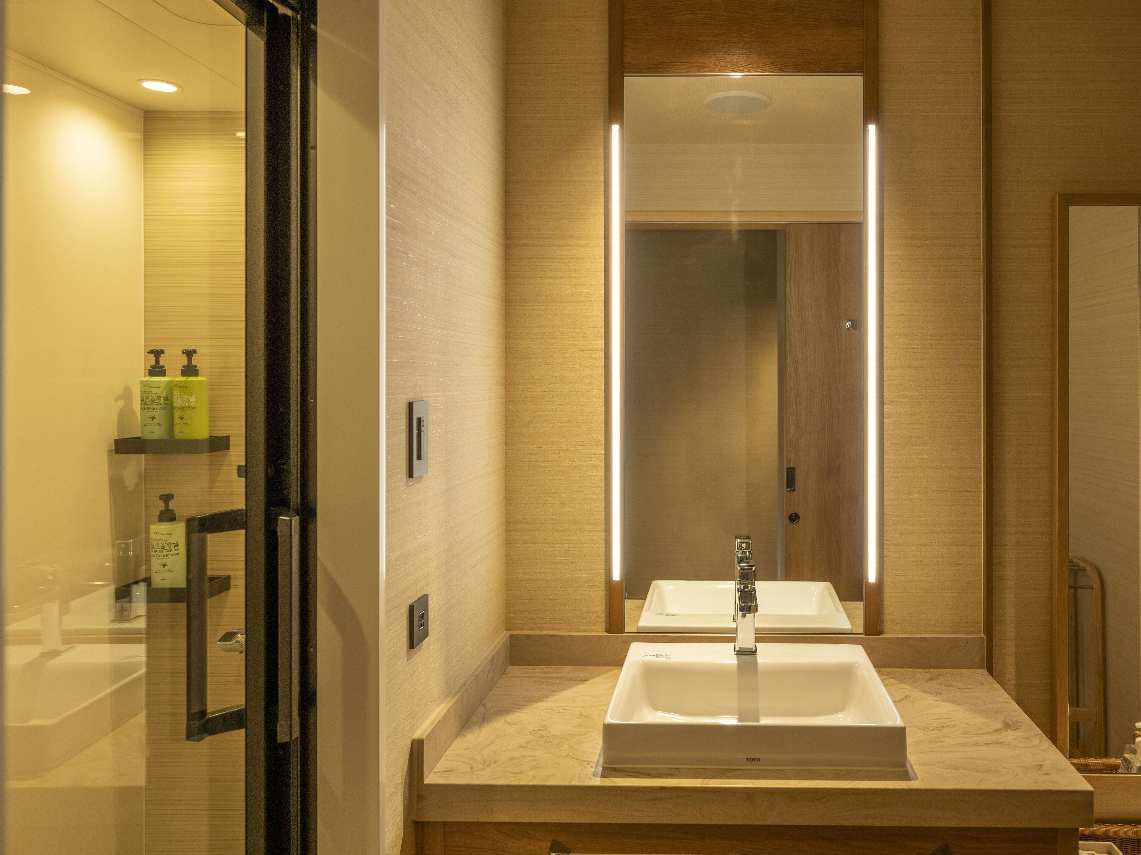 A modern bathroom with a large mirror, a sink, and a glass shower enclosure.