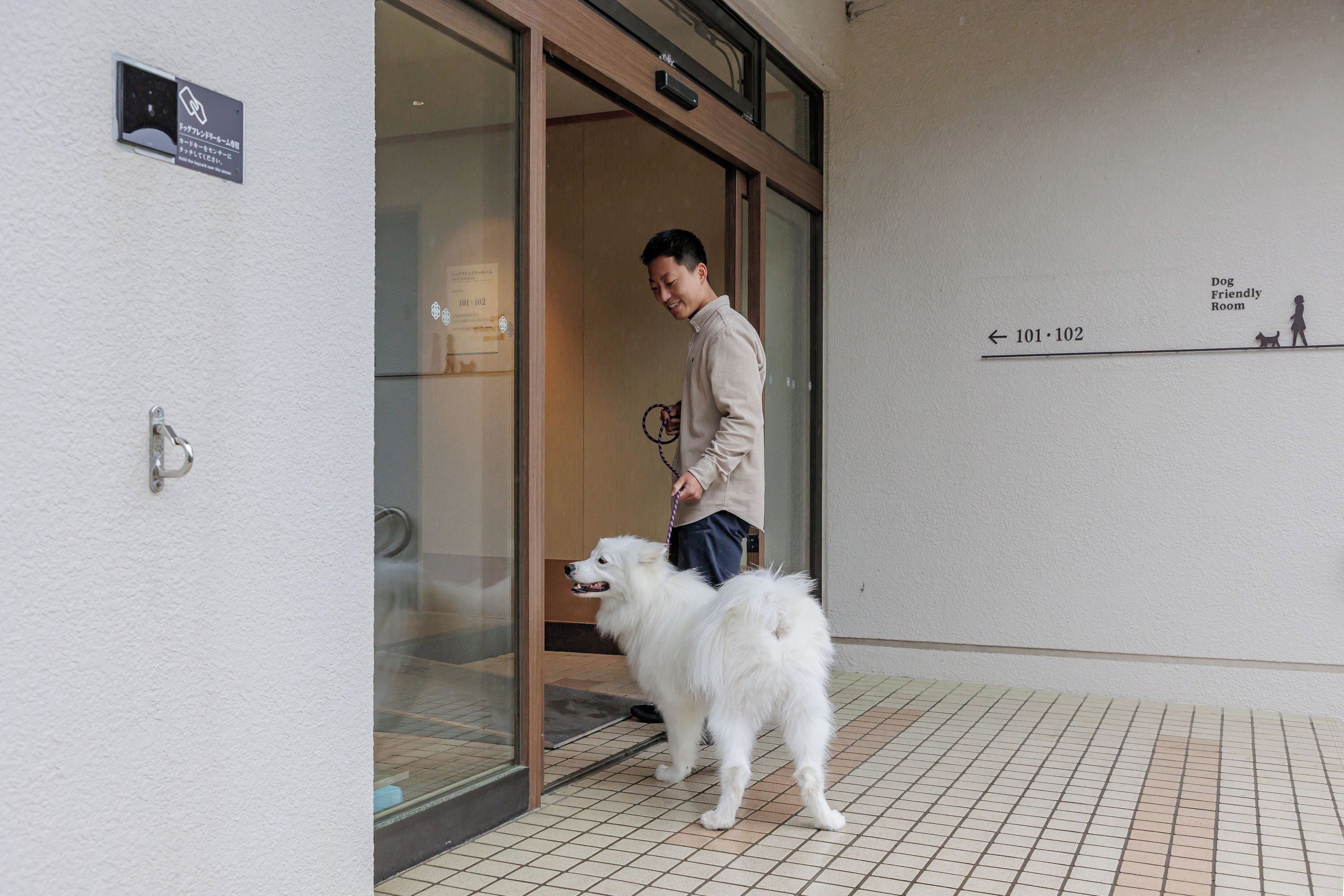Una persona con un perro frente a la entrada de un edificio.