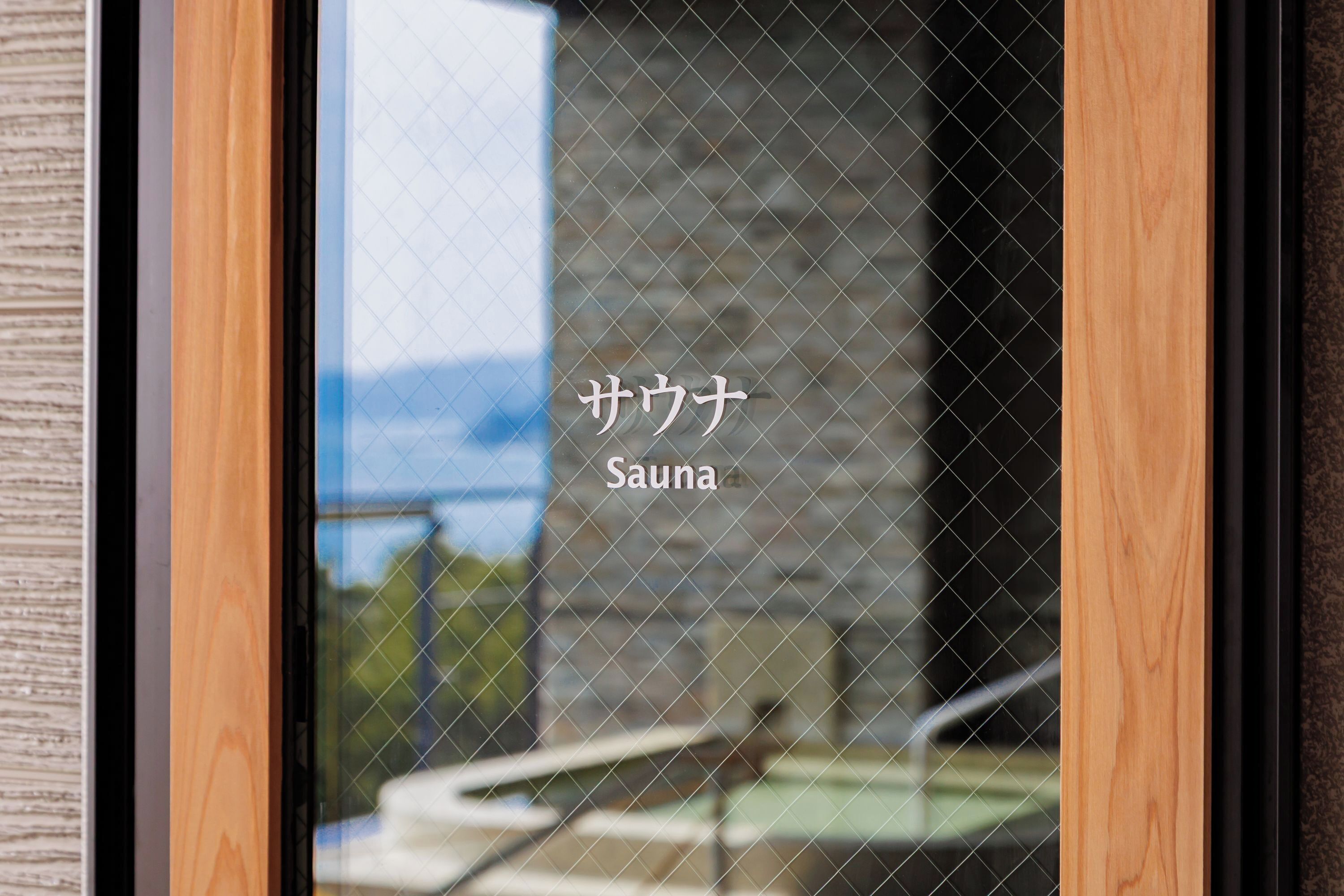 Una finestra con la scritta "Sauna" e vista su un edificio con piscina.