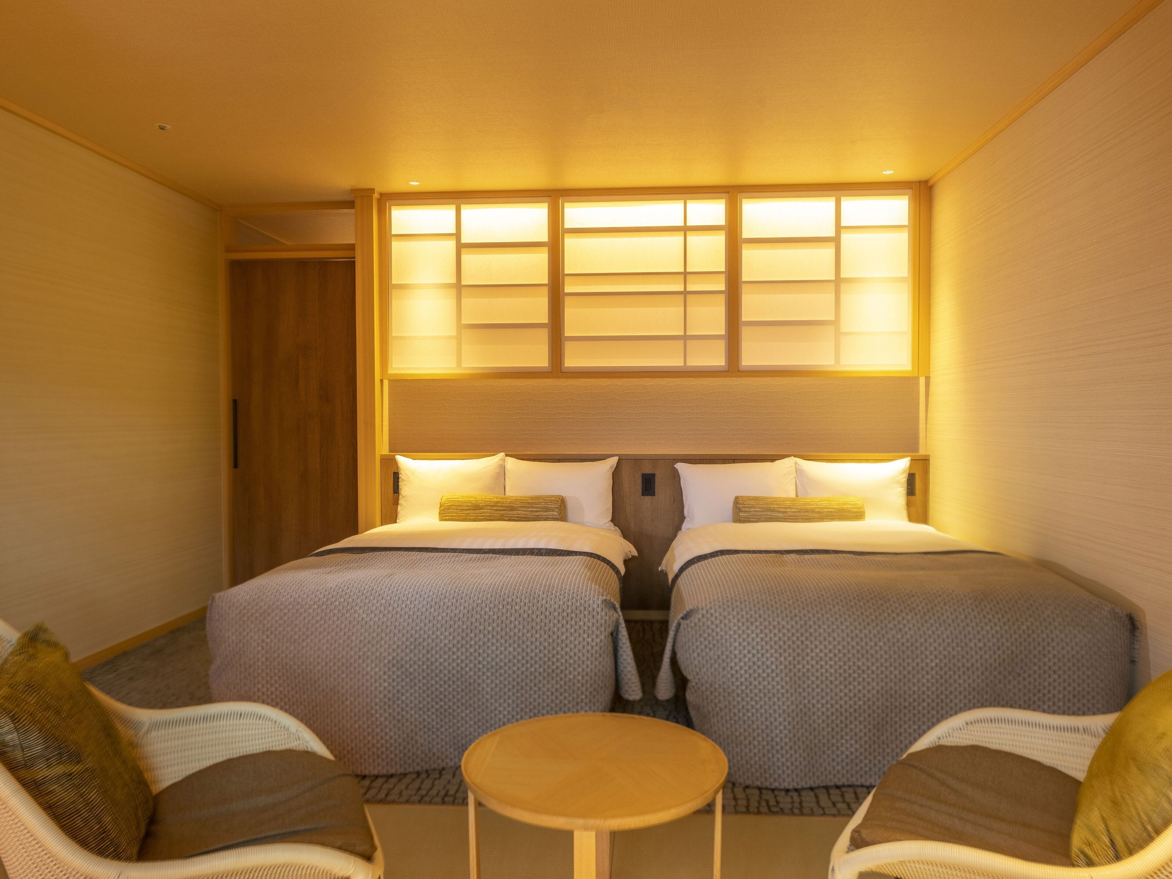 A hotel room with two beds, a small round table, and two chairs.