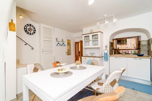 Un coin repas avec une table blanche, des chaises et une horloge au mur.