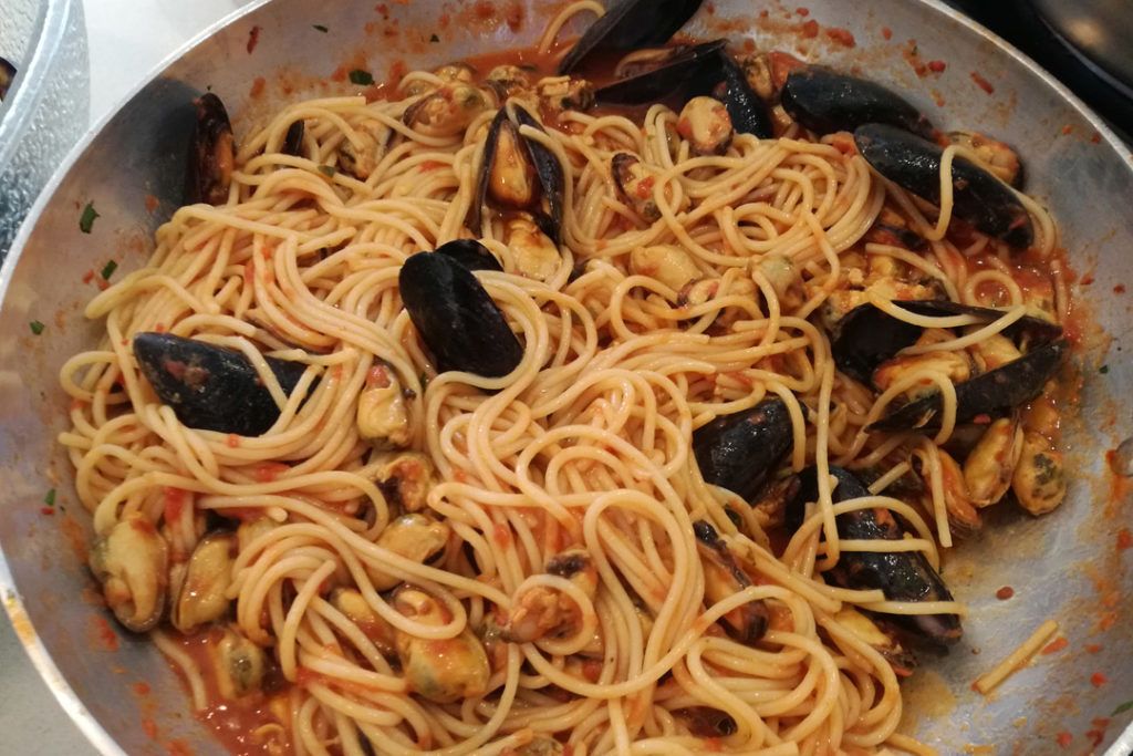 Una padella di spaghetti con cozze in salsa di pomodoro.