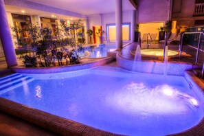 An indoor swimming pool with a hot tub, surrounded by plants and lounge chairs. - Hotel Alda Amelia (Cattolica)