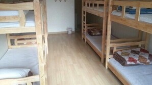 A room with bunk beds, wooden flooring, and a wall with a geometric pattern. - Jeonju Nangman Sidai Guesthouse - Hostel (Jeonju)