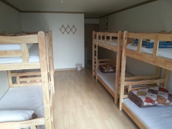 A room with bunk beds, wooden flooring, and a wall with a geometric pattern. - Jeonju Nangman Sidai Guesthouse - Hostel (Jeonju)