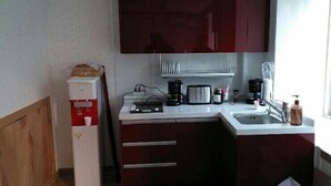 A compact kitchen with a refrigerator, coffee maker, toaster, and sink. - Jeonju Nangman Sidai Guesthouse - Hostel (Jeonju)