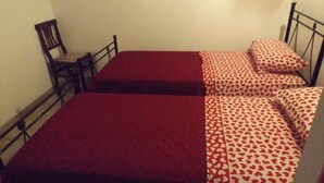 A small, single-room accommodation with two beds, each with a red and patterned bedspread. - Red Cottage Country House (Vico)