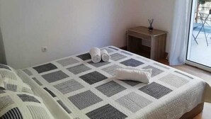 A bedroom with a bed, a painting, a TV, and a small table with a candle. - Lovely Studio in Omonoia (Athens)