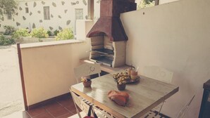 A patio with a wooden table, a pizza oven, and a bowl of olives.