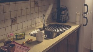 A kitchen with a sink, a coffee maker, and a white refrigerator.
