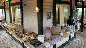 A buffet setup with various food items and beverages, a coffee machine, and a refrigerator. - Gästehaus am See (Gaienhofen)