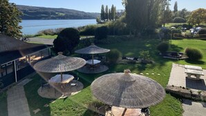 A patio area with outdoor seating and umbrellas overlooking a lake. - Gästehaus am See (Gaienhofen)