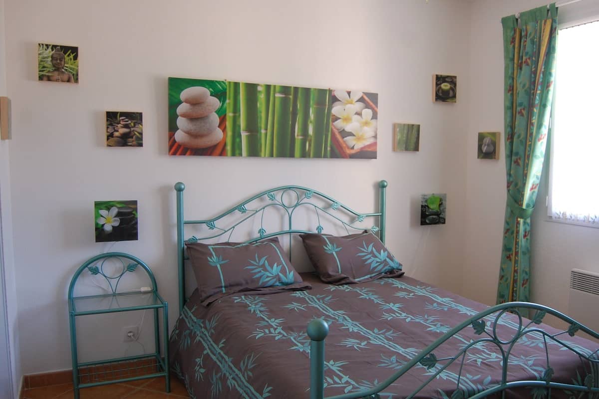 A bedroom with a bed, a bedside table, and a wall with framed pictures.