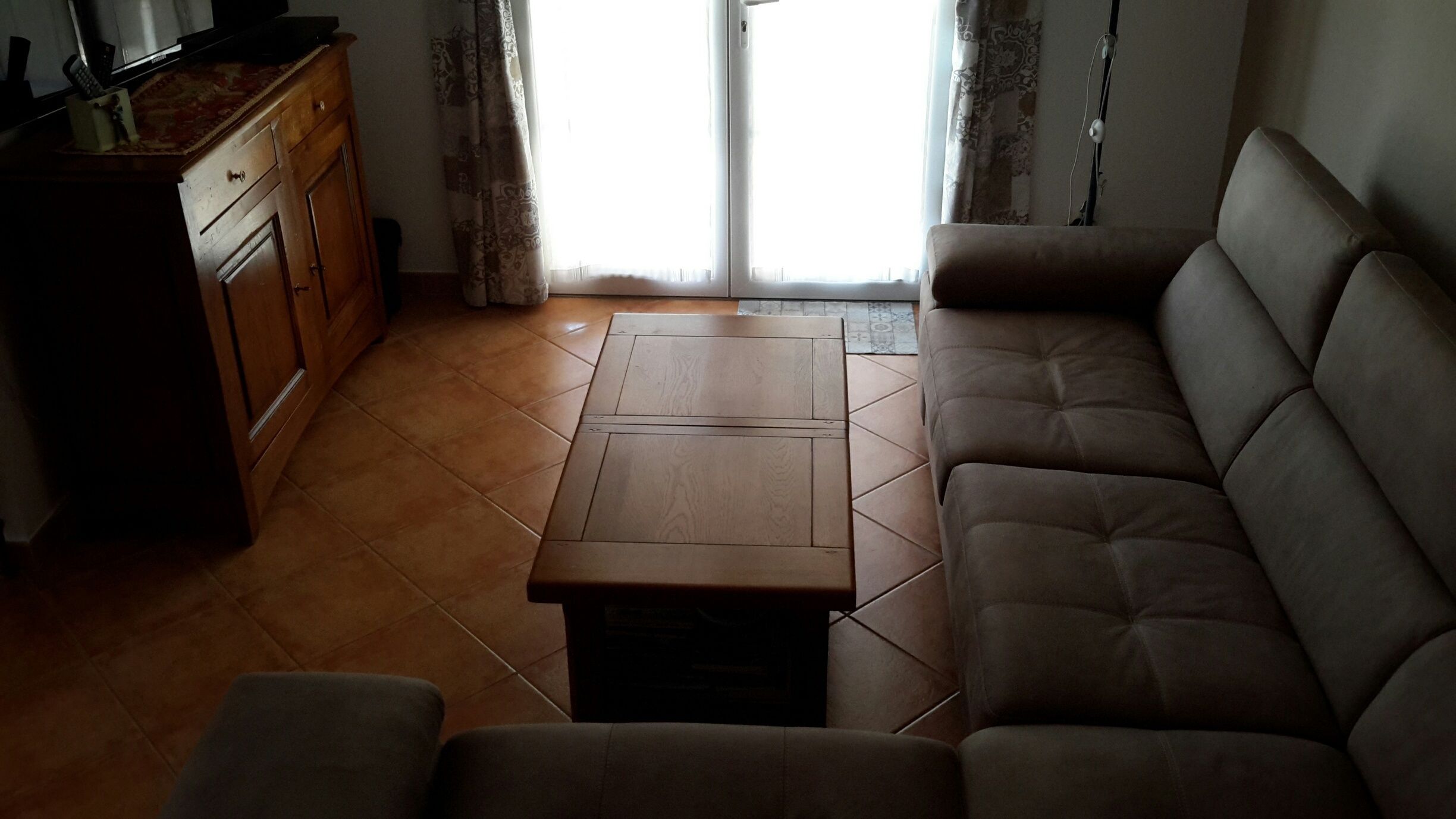 A living room with a sofa, a coffee table, and a wooden cabinet.