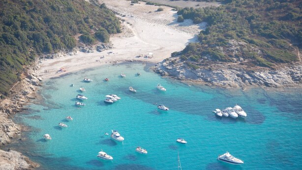 Vista aérea de una zona costera con barcos amarrados cerca de la orilla y una playa de arena.