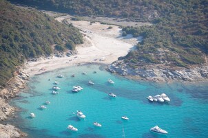 Vista aérea de una zona costera con barcos amarrados cerca de la orilla y una playa de arena.