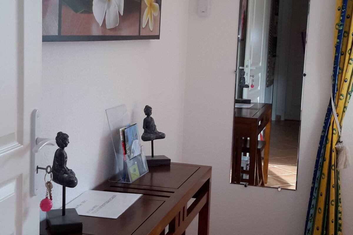 A room with a wooden desk, a mirror, a wall-mounted air conditioner, and a door with a yellow curtain.