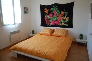 A bedroom with a bed, two bedside tables, a tapestry, and a window. - Villa Aghjanella (Patrimonio)