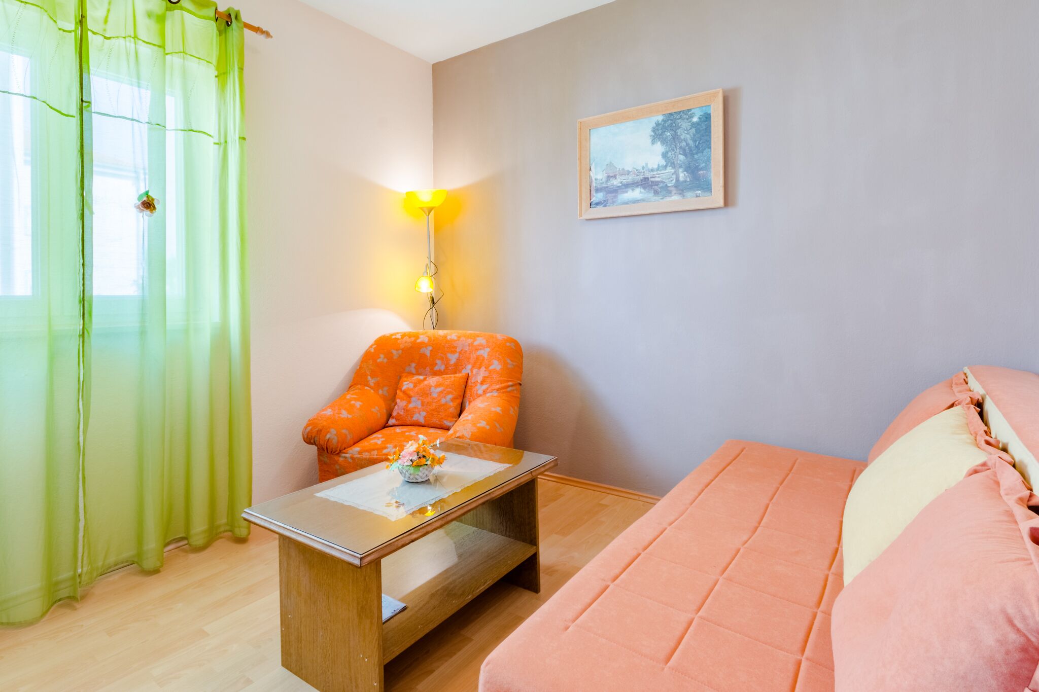 Une pièce comprenant un lit, une chaise, une table, une lampe et un tableau accroché au mur.