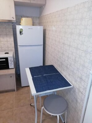 Compact kitchen with a refrigerator, microwave, and table for dining.