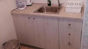 A small kitchenette with a sink, a coffee maker, a kettle, and a trash bin. - Margaritas house (Athens)