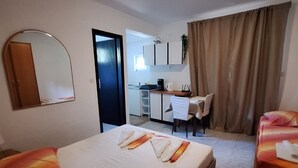 A hotel room with two beds, a desk, and a kitchenette. - Apartments Dalmatin Žuljana - Studio Apartment 2 (Zuljana)