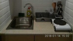 A kitchen with wooden cabinets, a stainless steel sink, a dish soap bottle, a dish rack, and a coffee maker. - Modern ideally located studio apartment (Athens)
