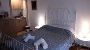 A bedroom with a bed, bedside tables, a wardrobe, and a small kitchen area. - Modern ideally located studio apartment (Athens)