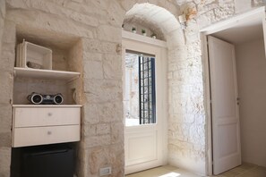 Cozy retreat with a white door, window, and shelf unit, featuring a small potted plant and a black appliance.