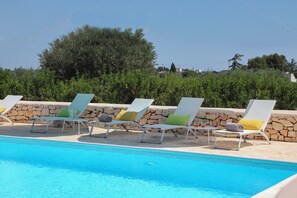 Una piscina al aire libre de temporada, sombrillas, tumbonas
