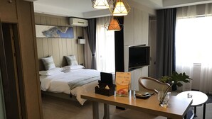 A hotel room with a bed, bedside table, TV, and a desk with a chair. - Metropolis Golf Hot Spring Hotel (Kunming)