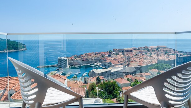 Ein Balkon mit freiem Blick auf eine Küstenstadt, darunter ein Hafen und historische Gebäude.