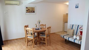 Un comedor con una mesa y sillas de madera, un sofá con funda estampada y un pequeño objeto decorativo sobre la mesa.
