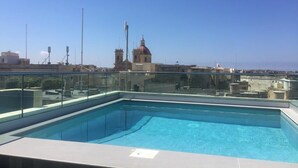 A rooftop swimming pool with a clear view of a historic building in the background. - Cittadella Boutique Living (Victoria)