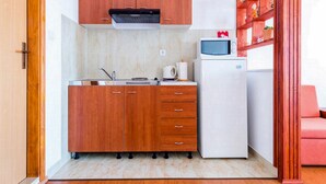 Une cuisine de taille réduite, avec des meubles en bois, un réfrigérateur blanc et un four à micro-ondes posé sur le plan de travail.