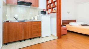 A compact kitchen with wooden cabinets, a white refrigerator, a microwave, and a sink. - Guest House Fontana - Studio Apartment with Sea View (2 Adults) (Mlini)