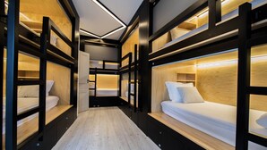 A modern hotel room with bunk beds, wooden flooring, and built-in lighting. - GiG Capsule Hostel (Mafra)