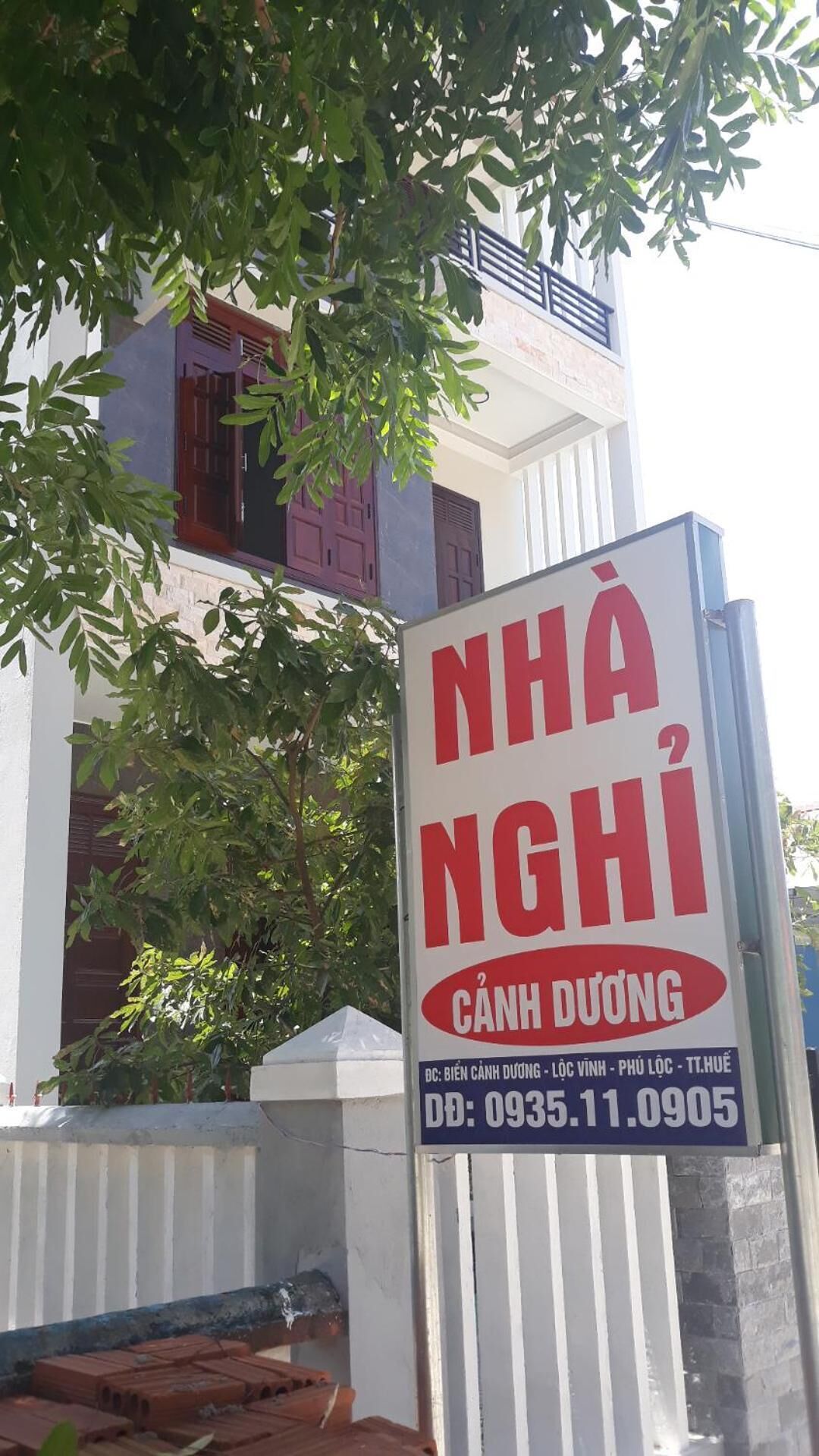 A signboard for NHÀ NGHI, a property in Cần Đuông, with contact details and location information.