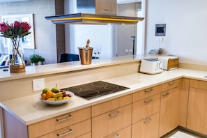 Enjoy cooking in this well-equipped kitchen with a stainless steel range hood, induction cooktop, and toaster.